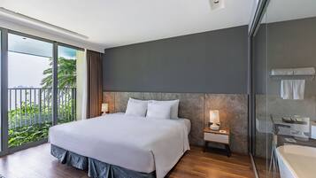 Ein modernes Hotelzimmer mit einem großen Bett, einer Glasdusche und einem Balkon mit Blick auf Grünflächen.