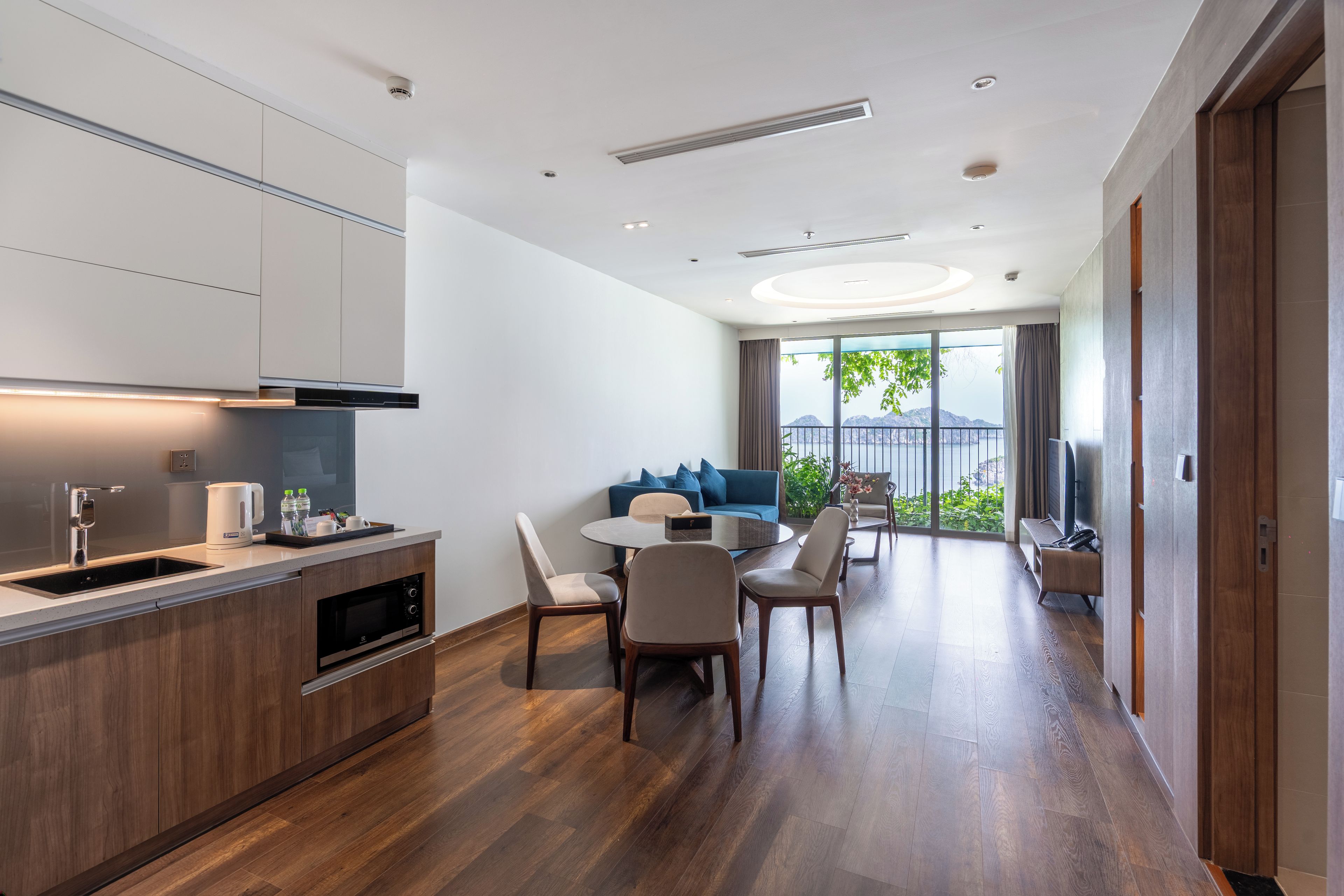 Una habitación de hotel moderna con kitchenette, zona de comedor y balcón con vistas.