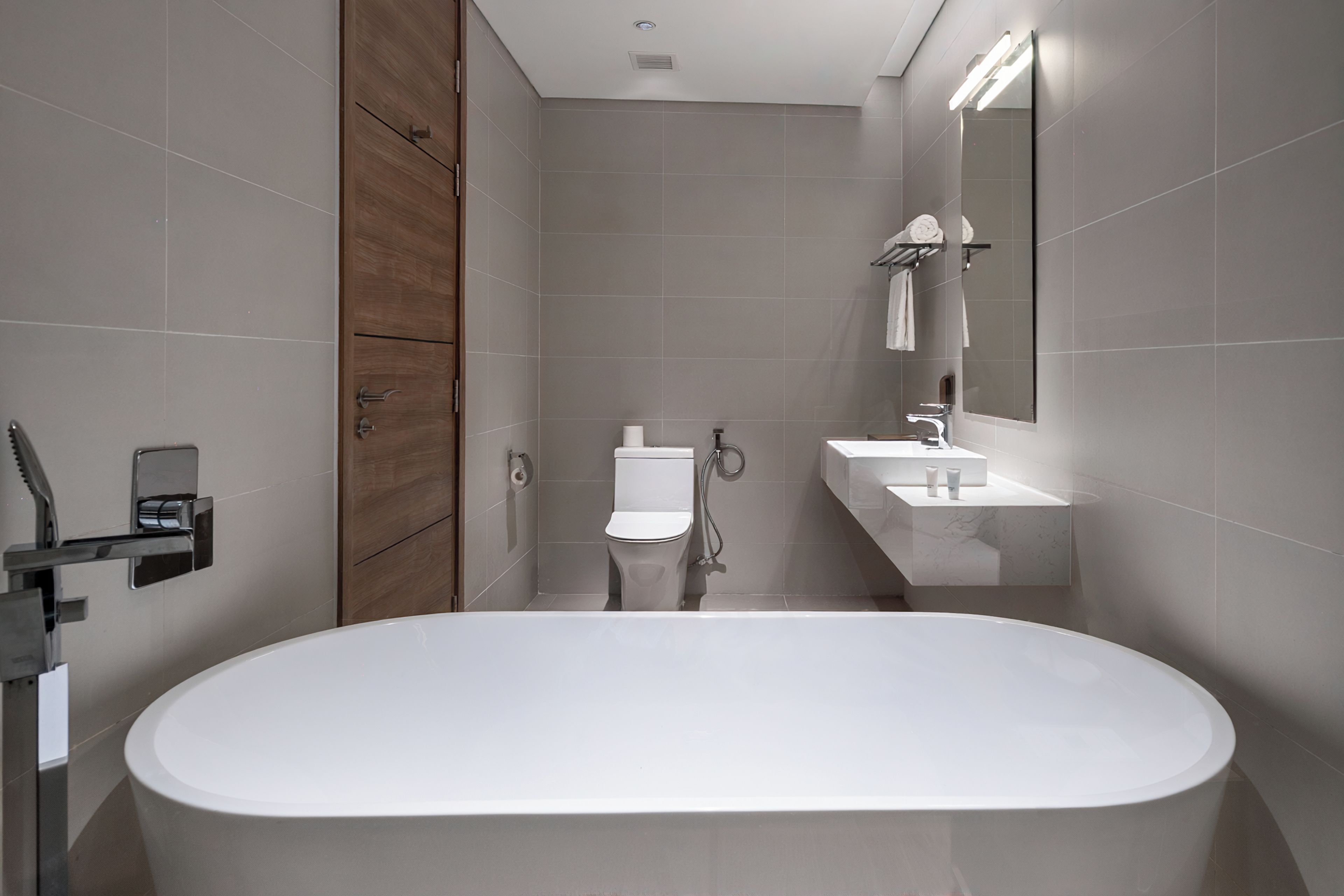Un baño moderno con una bañera independiente, inodoro y lavamanos con espejo.
