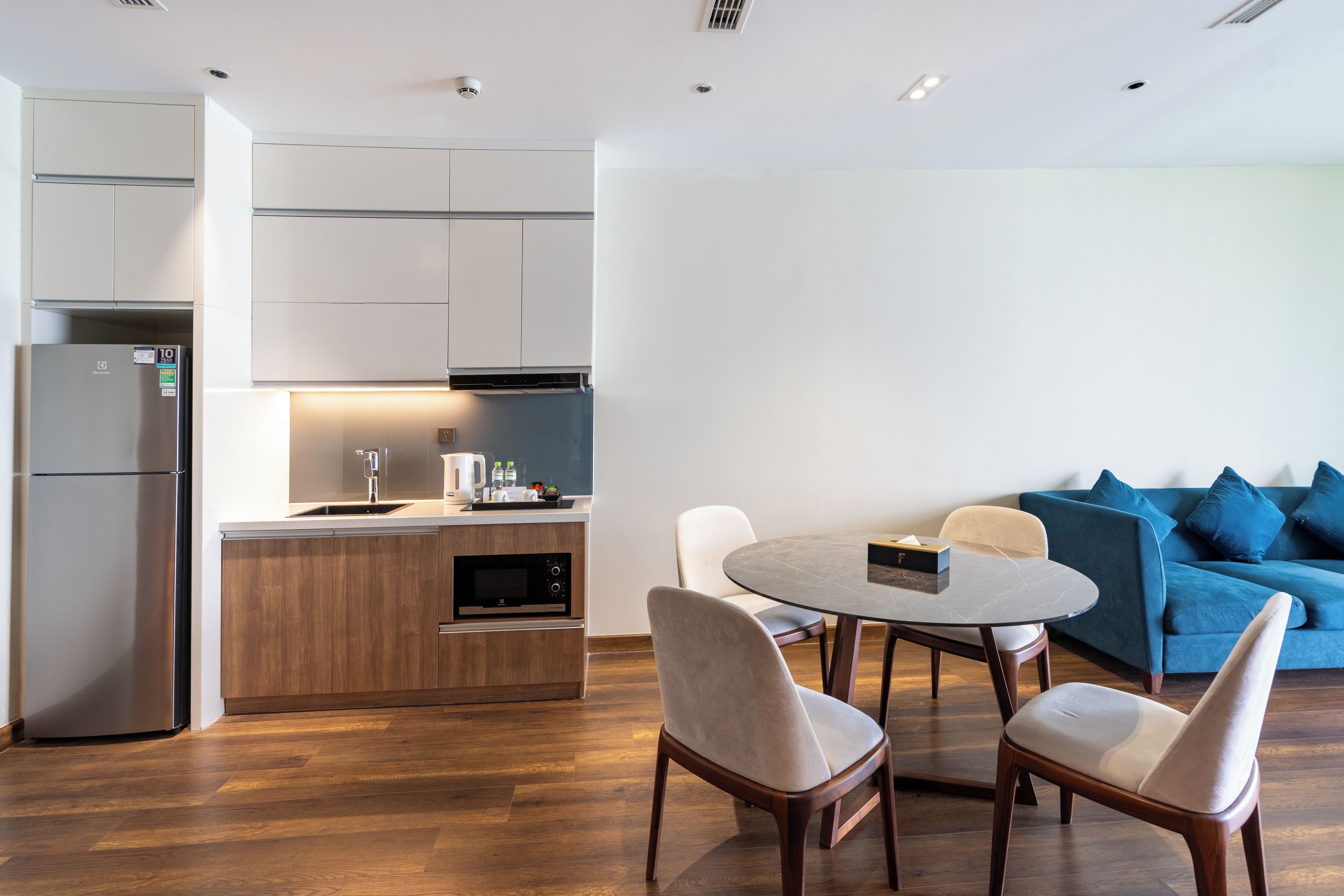 Una cocina moderna con horno empotrado, refrigerador y comedor con mesa redonda y sillas.