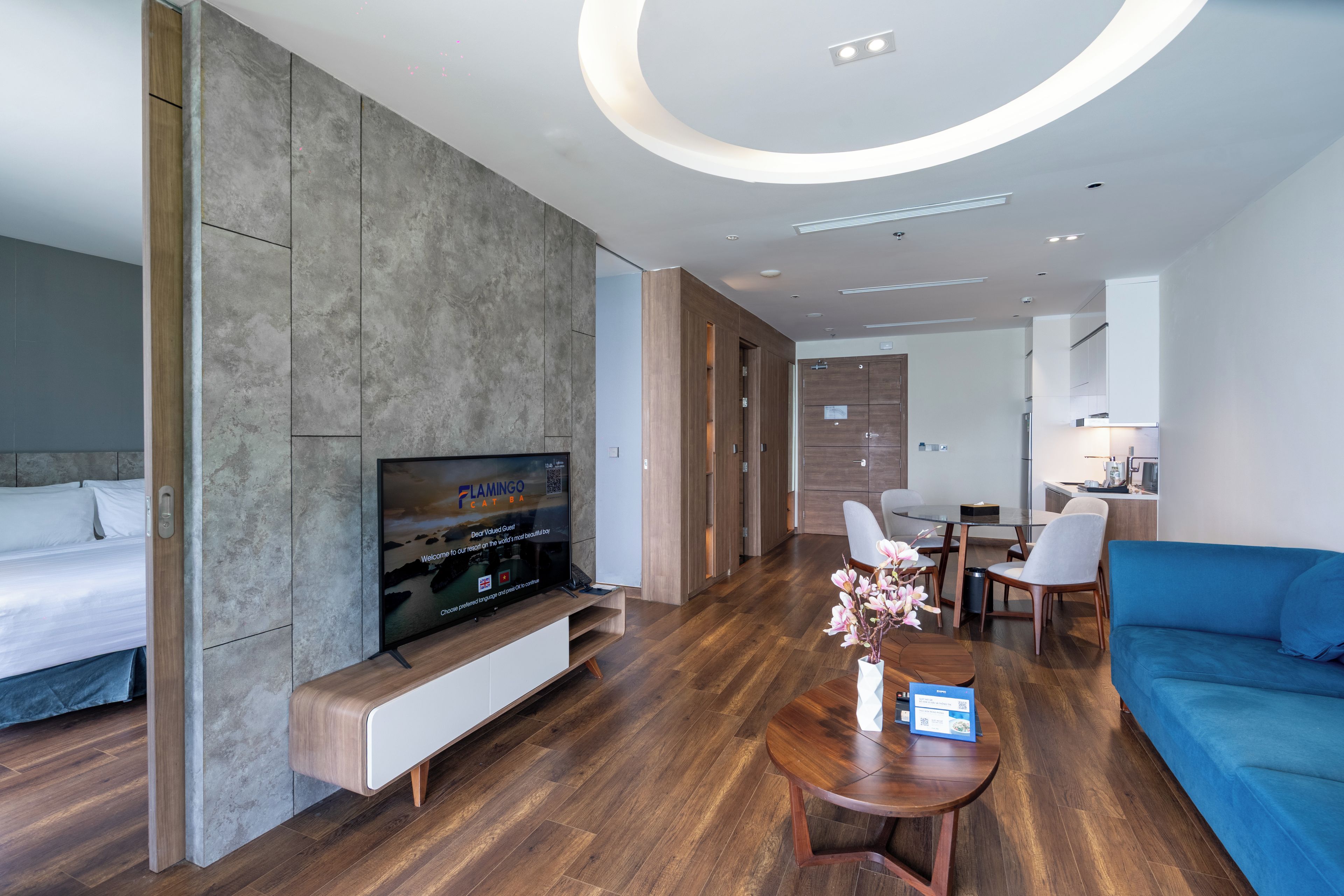 Una habitación de hotel moderna con televisión de pantalla plana, un sofá, zona de comedor y cocina.