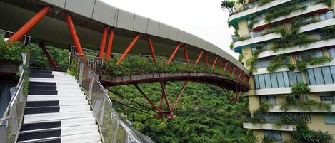 Eine Fußgängerbrücke mit geschwungener Form, die zwei Gebäude mit Balkonen verbindet.