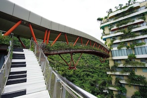 A pedestrian bridge with a curved design, connecting two buildings with balconies. - Vela Cat Ba Beach Resort - Flamingo Sea & Sand (Cat Hai)