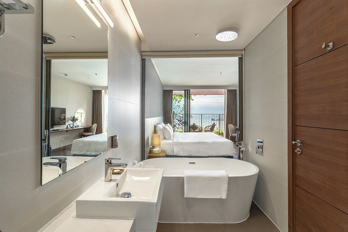 A modern bathroom with a large bathtub, a sink, and a mirror.