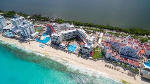 Um hotel à beira-mar com vários edifícios, praia e área de piscina.
