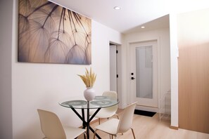 A modern dining area with a glass table, white chairs, and a vase with dried plants. - Serene 2-bedroom apartment with AC in charming Delta (Delta)