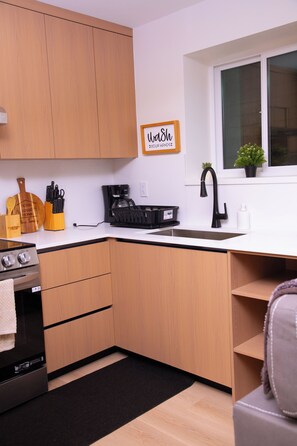 A modern kitchen with wooden cabinets, a coffee maker, a sink, and a potted plant. - Serene 2-bedroom apartment with AC in charming Delta (Delta)