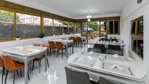 En restaurant med flere borde og stole, store vinduer og udsigt ud