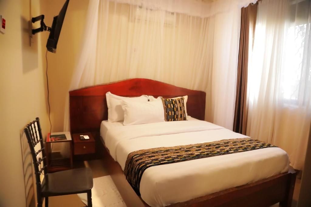 Une chambre d’hôtel avec un lit, une chaise, une table de chevet et une lampe.