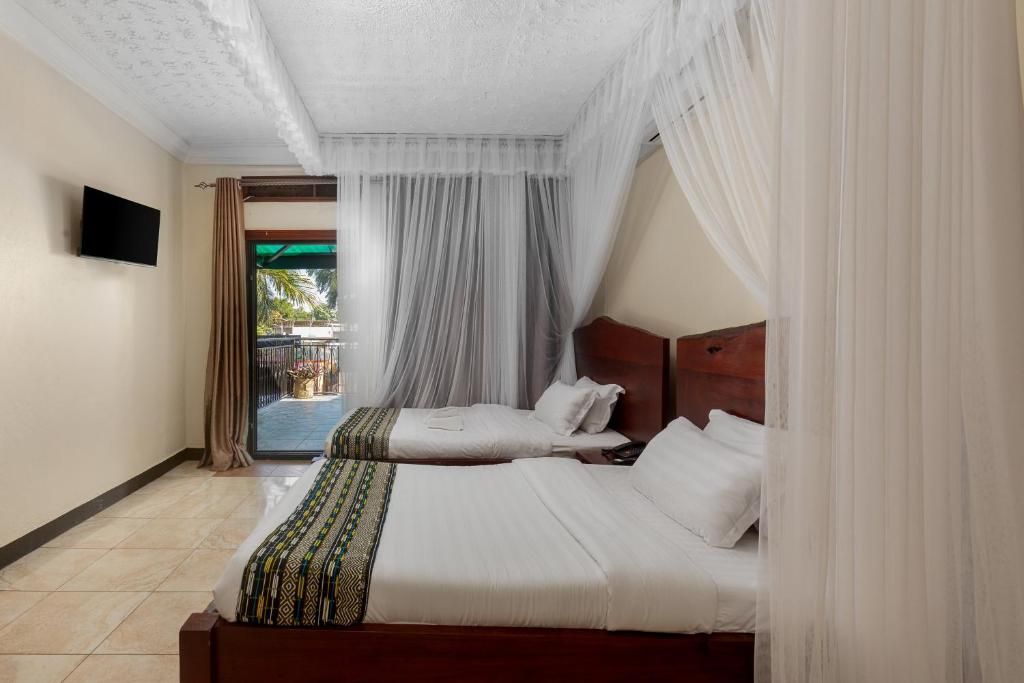Een hotelkamer met twee bedden, een televisie en een balkon met gordijnen.