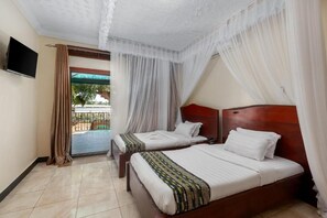 Habitación de hotel con dos camas, televisión y balcón con cortinas.