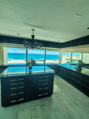 A modern room with a large window, a pool table, and a chandelier. - Luxury beachfront suite with a hot tub (Cancún)