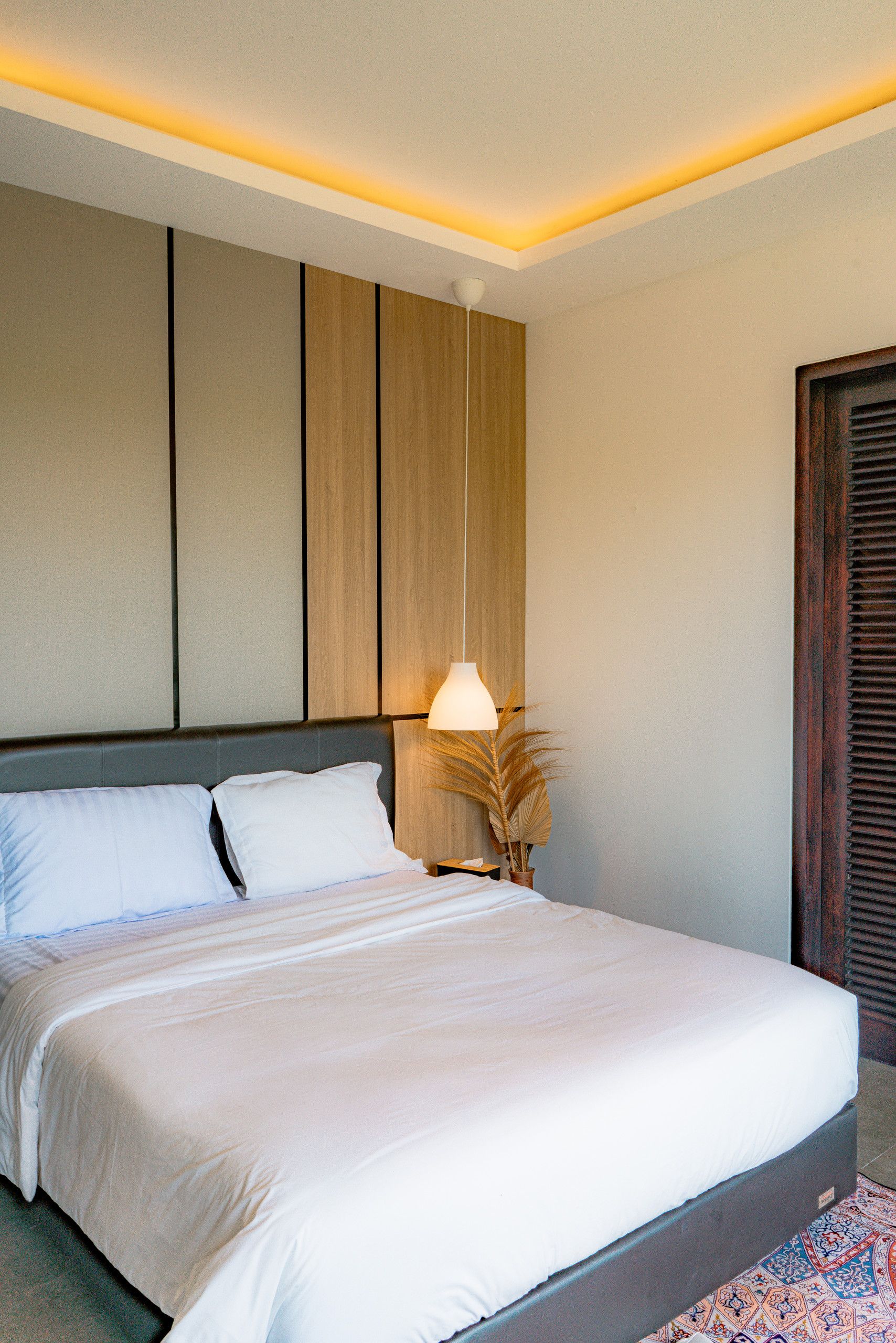 Een hotelkamer met een groot bed, een bedlampje en een houten hoofdbord.
