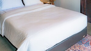 Quarto de hotel com uma cama grande, luminária de cabeceira e cabeceira de madeira.