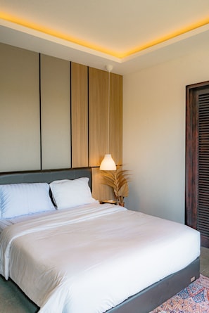 Een hotelkamer met een groot bed, een bedlampje en een houten hoofdbord.