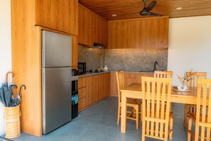 Une cuisine compacte dotée de meubles en bois, d’un réfrigérateur en acier inoxydable et d’un coin repas avec des chaises et une table en bois.