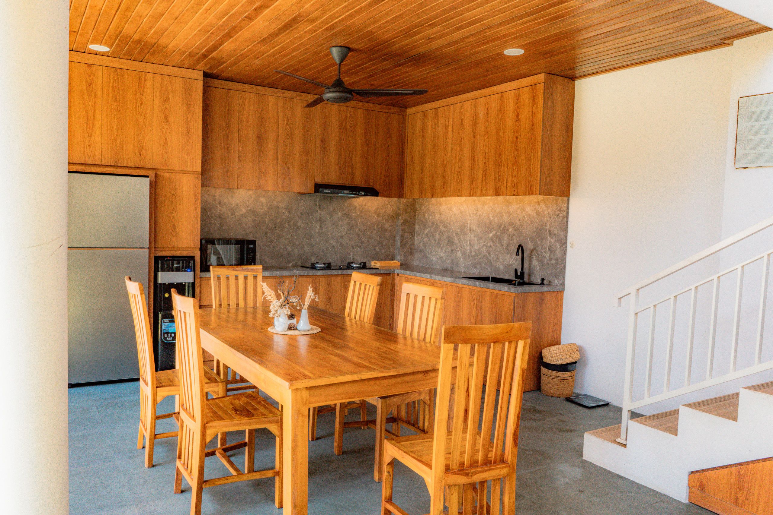 Cozinha compacta com armários de madeira, mesa e cadeiras.