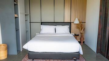 Un dormitorio moderno con una cama grande, una mesita de noche, una lámpara y un jarrón decorativo.
