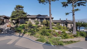 A two-story stone building with a stone staircase leading to the entrance, surrounded by lush greenery and a clear sky. - Hyatt Highlands Inn Spa Townhome Sept 19-26, 2026, Carmel Highlands, ocean view (Carmel)