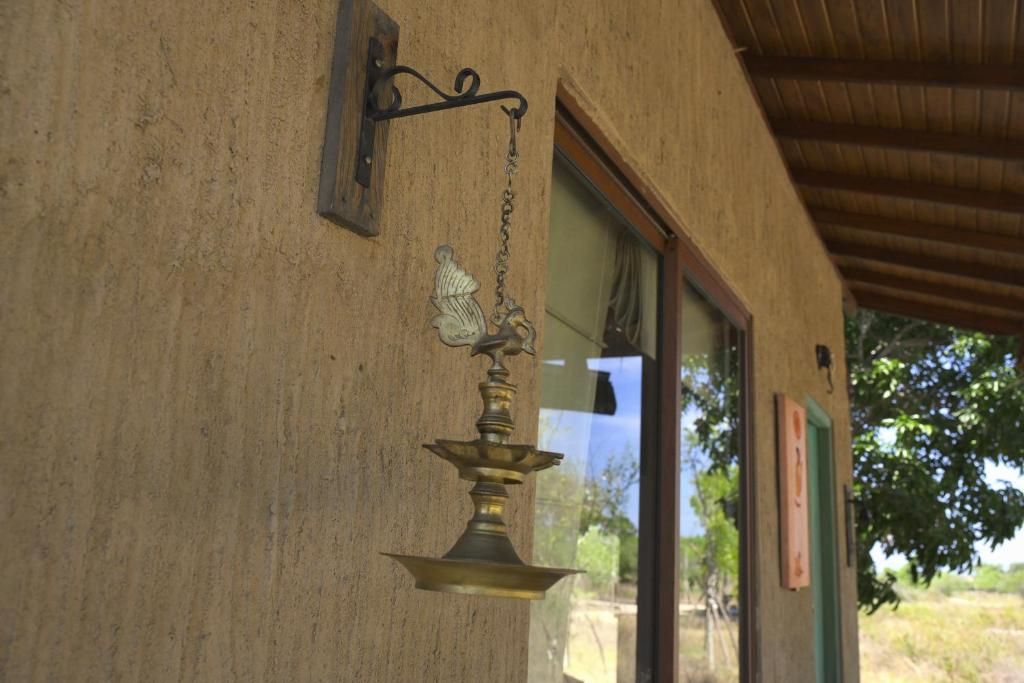 A brass wall-mounted object with a chain, attached to a wall with a window and a door.