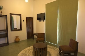 A room with a round table, two chairs, a mirror, a television, and a door.