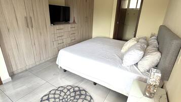 A bedroom with a bed, a ceiling fan, a TV, and a wardrobe.