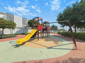 Un parque infantil con un tobogán amarillo y una estructura de escalada roja.