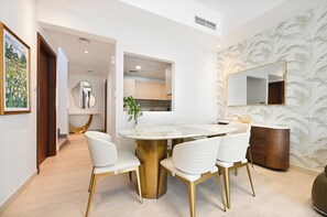 A modern dining area with a round table, white chairs, and a gold base. - Luxury 5-Bedroom Townhouse with Private Pool in Dubai (Dubai)