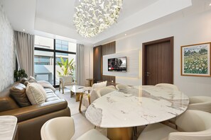 A modern living room with a marble dining table, leather sofa, and a television mounted on the wall. - Luxury 5-Bedroom Townhouse with Private Pool in Dubai (Dubai)
