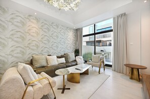 A modern living room with a leather sofa, white armchairs, a marble coffee table, and a large window with a view of a building. - Luxury 5-Bedroom Townhouse with Private Pool in Dubai (Dubai)