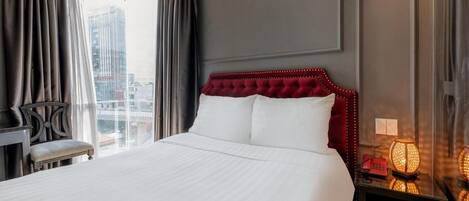A hotel room with a large bed, a desk, and a nightstand with a lamp.