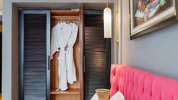 Een kamer met een bed, een houten garderobe en een wandlamp.