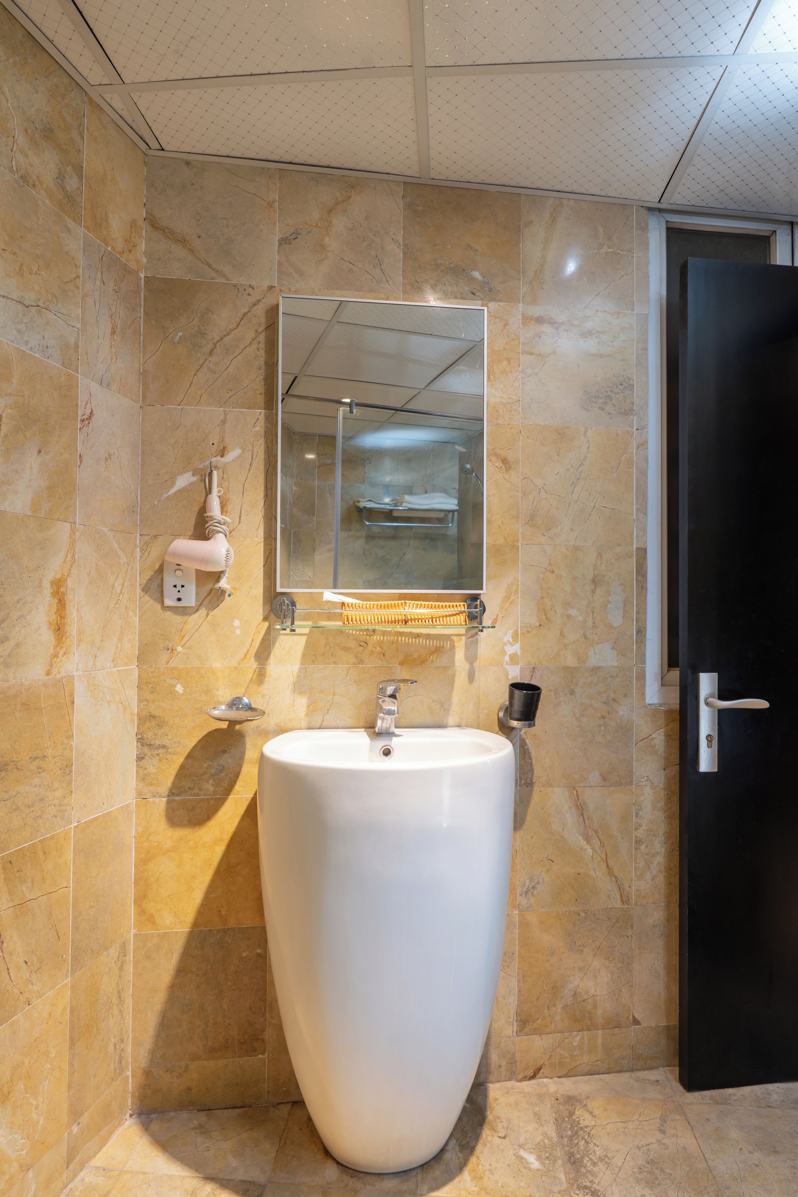 A bathroom with a large white sink, a mirror, and a shower enclosure.