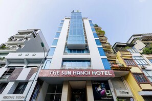 Um hotel com vários andares e um letreiro chamativo para 'The Sun Hanoi Hotel' no térreo.