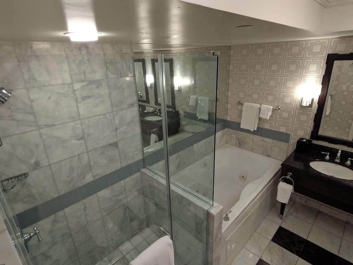 A modern bathroom with a glass-enclosed shower, a separate bathtub, and a black vanity with a sink.
