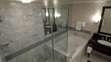 A modern bathroom with a glass-enclosed shower, a separate bathtub, and a black vanity with a sink.