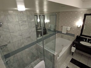 A modern bathroom with a glass-enclosed shower, a separate bathtub, and a black vanity with a sink. - 1-bedroom hotel suites - For KINGS (Paradise)