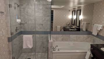 A modern bathroom with a glass-enclosed shower, a freestanding bathtub, and a vanity with a mirror.