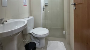 Un baño con lavamanos, inodoro y zona de ducha con mampara de vidrio.