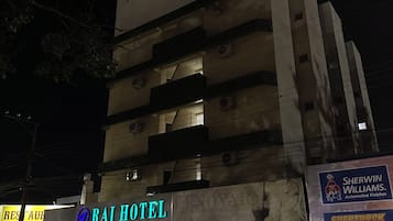A multi-story building with a sign for 'Rai Hotel' at the ground level, featuring a contact number.