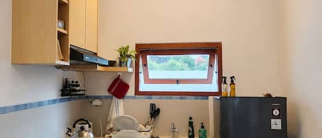 Une cuisine compacte équipée d’une cuisinière à gaz, d’un réfrigérateur, d’une fenêtre avec vue et d’un luminaire suspendu.