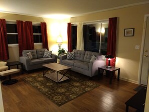 Ein Wohnzimmer mit zwei Sofas, einem Couchtisch, einer Lampe und einem Teppich.
