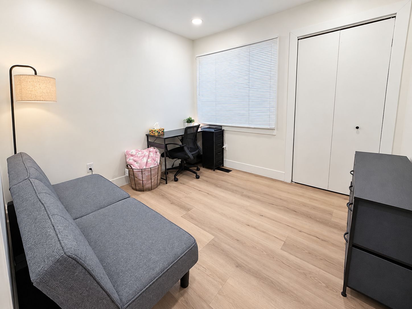 A room with a bed, a desk, a chair, a lamp, and a wardrobe.