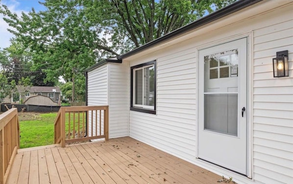 A single-story house with a wooden deck, a front door with a glass panel, and a small attached garage.