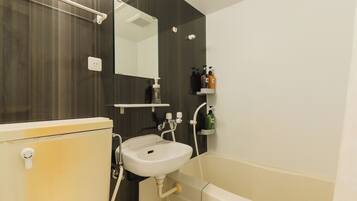 A bathroom with a toilet, sink, and bathtub. There is a mirror above the sink and a shelf with toiletries.