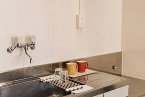 A kitchen sink with a faucet, a coffee maker, and two mugs on the counter. - ishigaki bus terminal inn (Ishigaki)