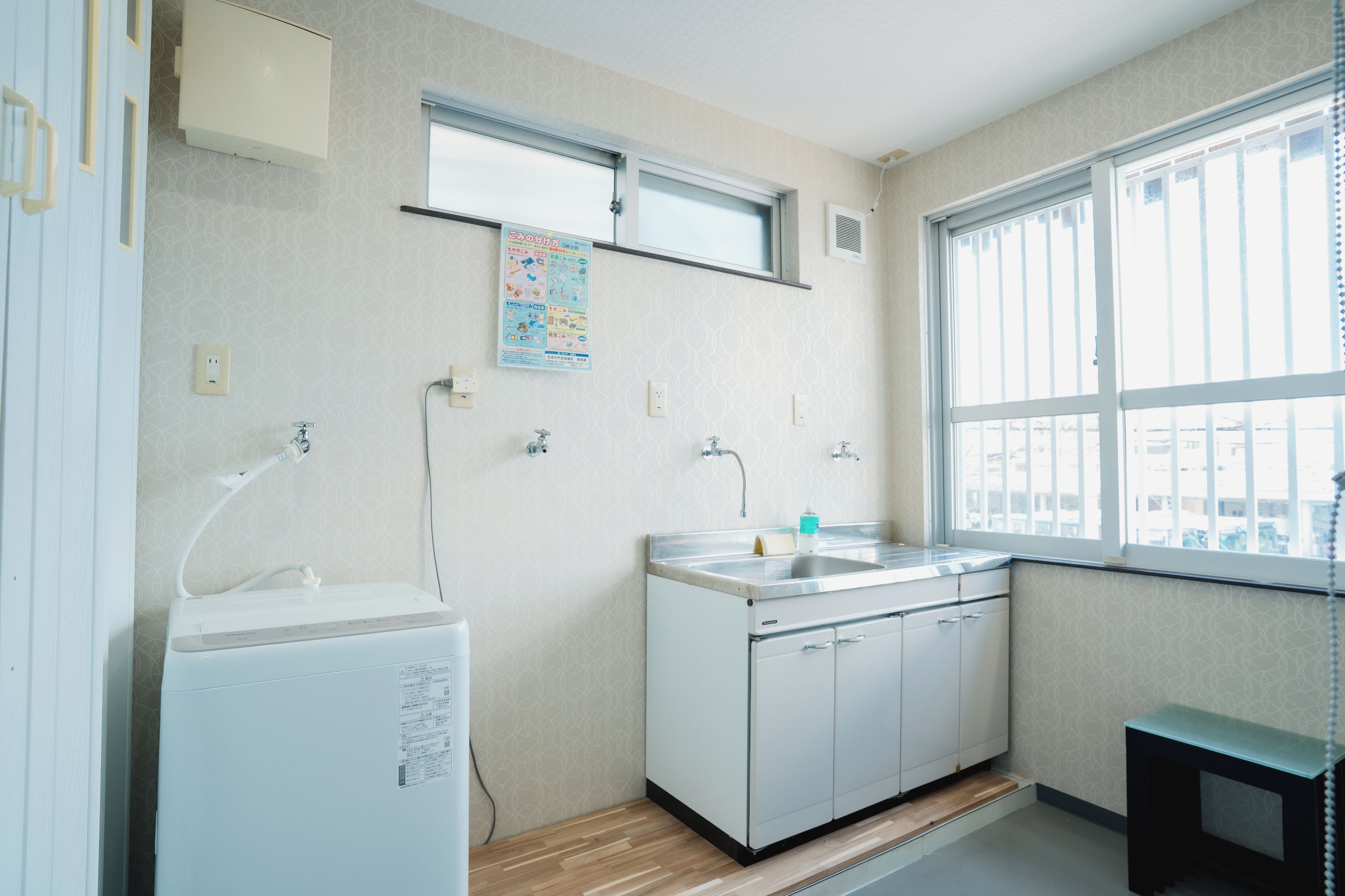 A small, well-lit kitchen with a window, a sink, and a white refrigerator.