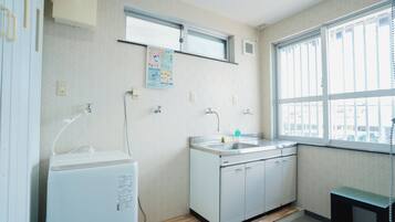 A small, well-lit kitchen with a window, a sink, and a white refrigerator.