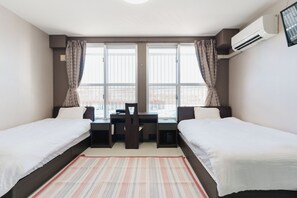 A hotel room with two single beds, a desk with a chair, and a large window with curtains. - ishigaki bus terminal inn (Ishigaki)