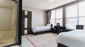 Een hotelkamer met een bed, een bureau, een stoel, een kledingkast en een groot raam.
